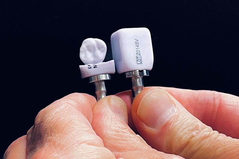 The image shows a close-up of a person s hand holding a small white object with a toothbrush head attached to it, which appears to be a makeshift cleaning tool.