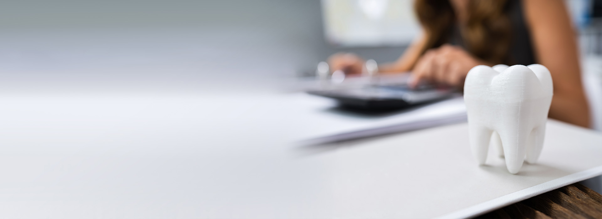 The image shows a person working at a desk with a laptop, a whiteboard, and a toothbrush holder in the foreground.