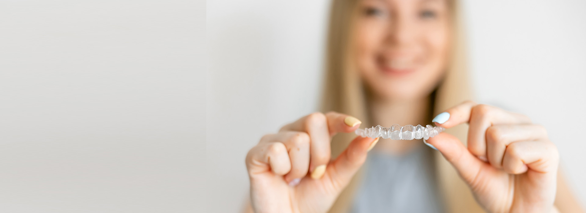 A woman is holding a small object, possibly jewelry or a ring, in front of her with both hands.