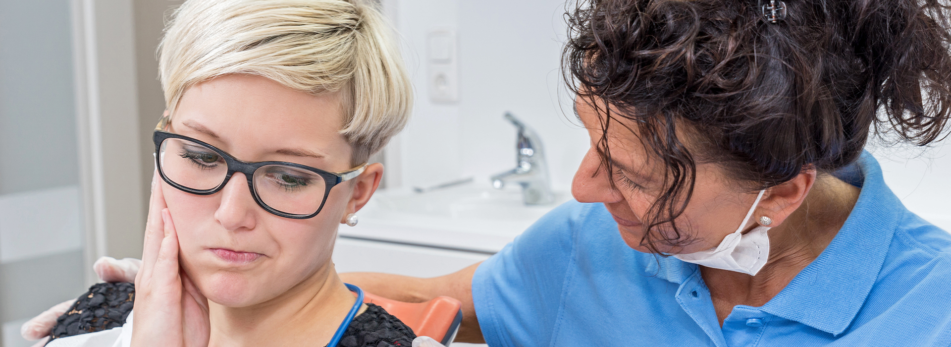 A woman receiving a dental cleaning from a professional, with a focus on the dental tools and equipment.