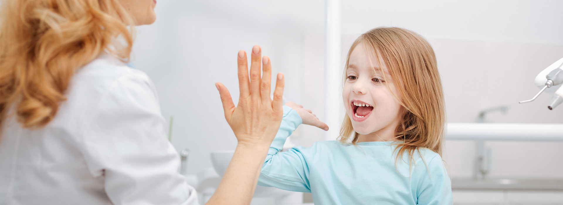 Woman and child in a bathroom, with the woman washing her hands and the child looking on.