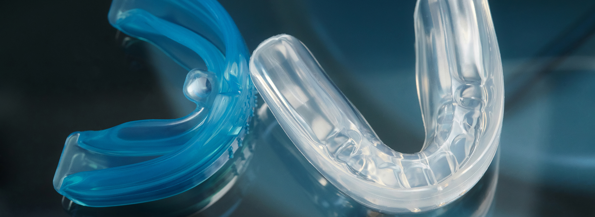 The image shows a close-up of a blue and clear plastic dental orthodontic appliance, commonly known as braces, with the letter  C  visible in the center.