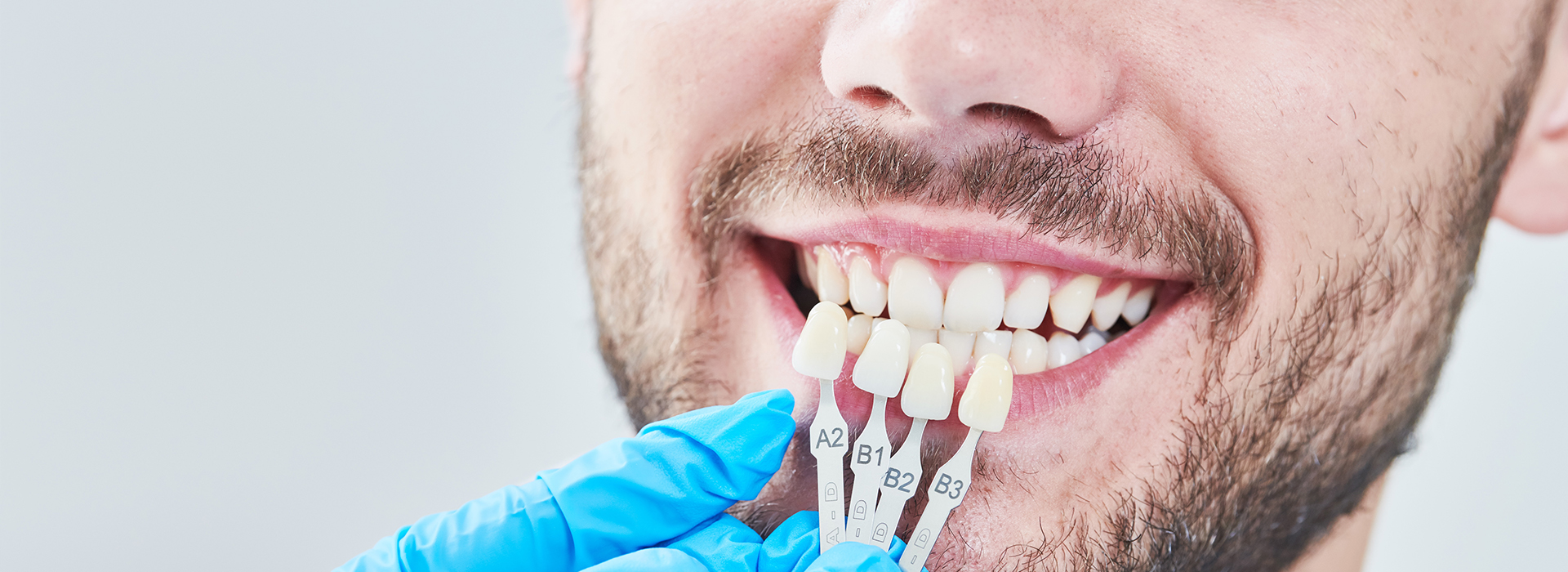 A man with a toothy smile wearing dental braces and a mouthguard.