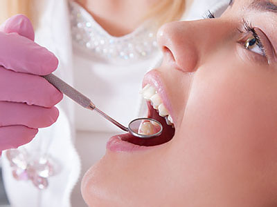 An image of a dental professional performing a dental procedure on a patient, with the dental professional holding a syringe and the patient s mouth open.