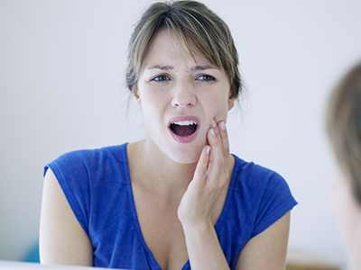 Woman with hand on face, looking concerned or surprised.