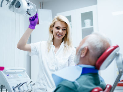 A dental hygienist assisting a patient in a dental chair.